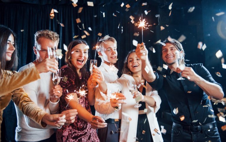 having-fun-with-sparklers-confetti-is-air-group-cheerful-friends-celebrating-new-year-indoors-with-drinks-hands